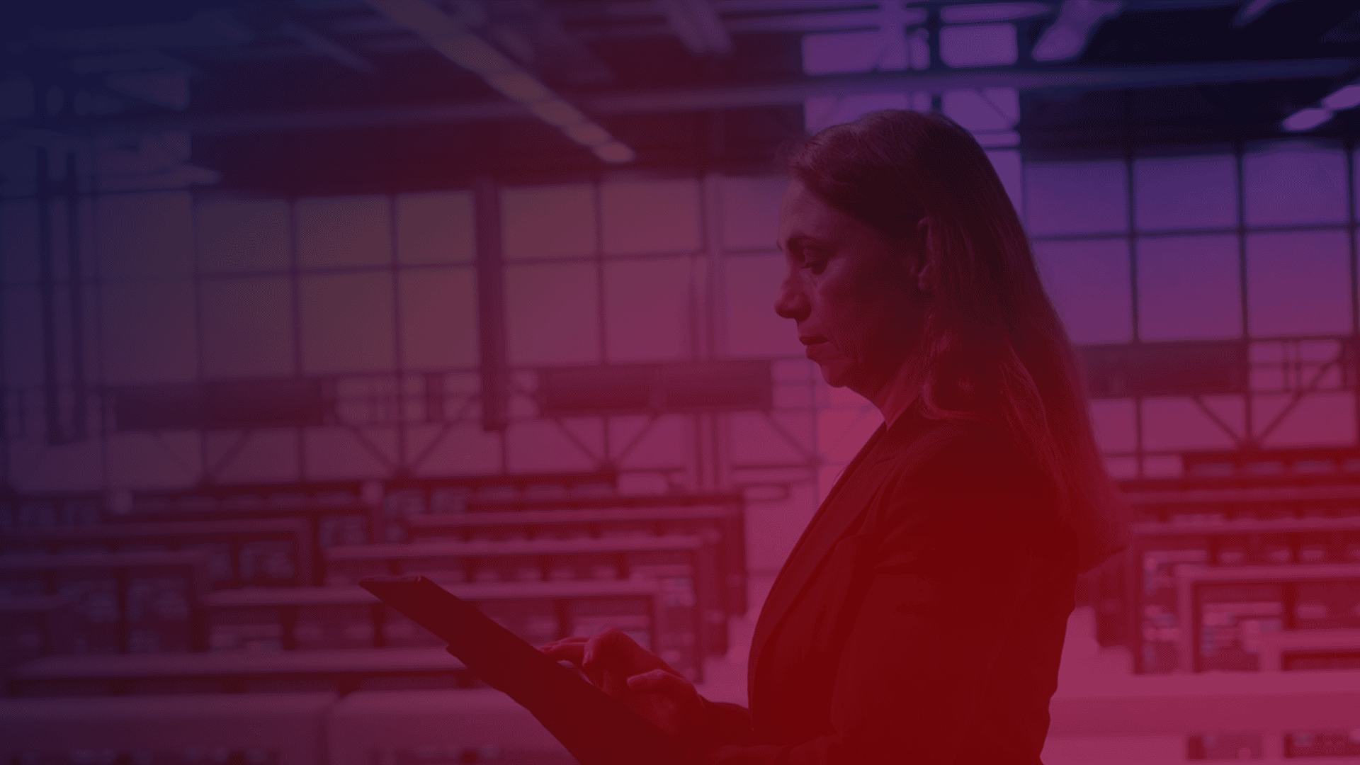 modernização de storage. Pessoa utilizando um tablet em um ambiente corporativo, com iluminação em tons de roxo e vermelho.